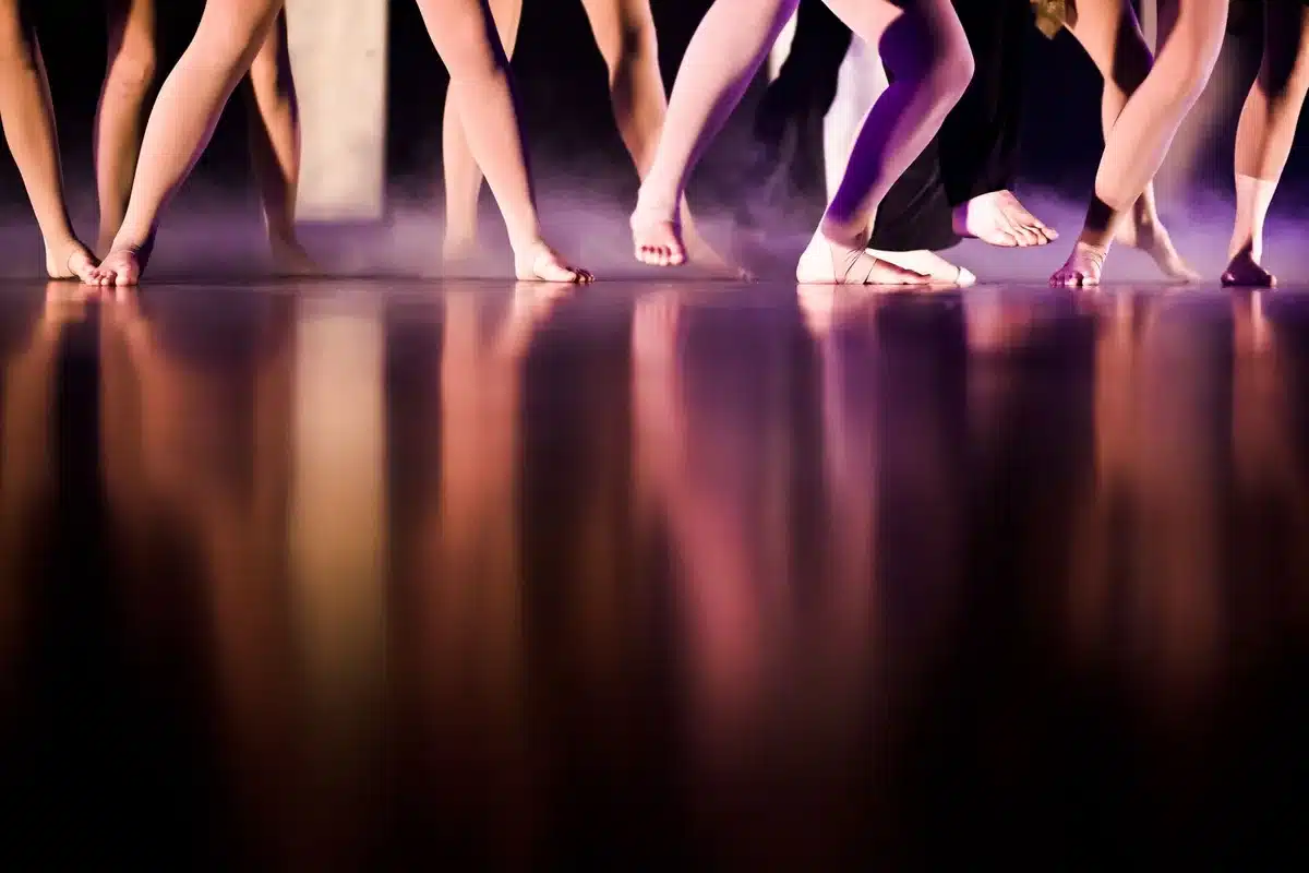 Silhouette di ballerina su palco con pellicola cinematografica sullo sfondo, simbolo del passaggio dalla danza al cinema