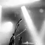 Palco da concerto vuoto con microfono e riflettori spenti, simbolo della sospensione del tour