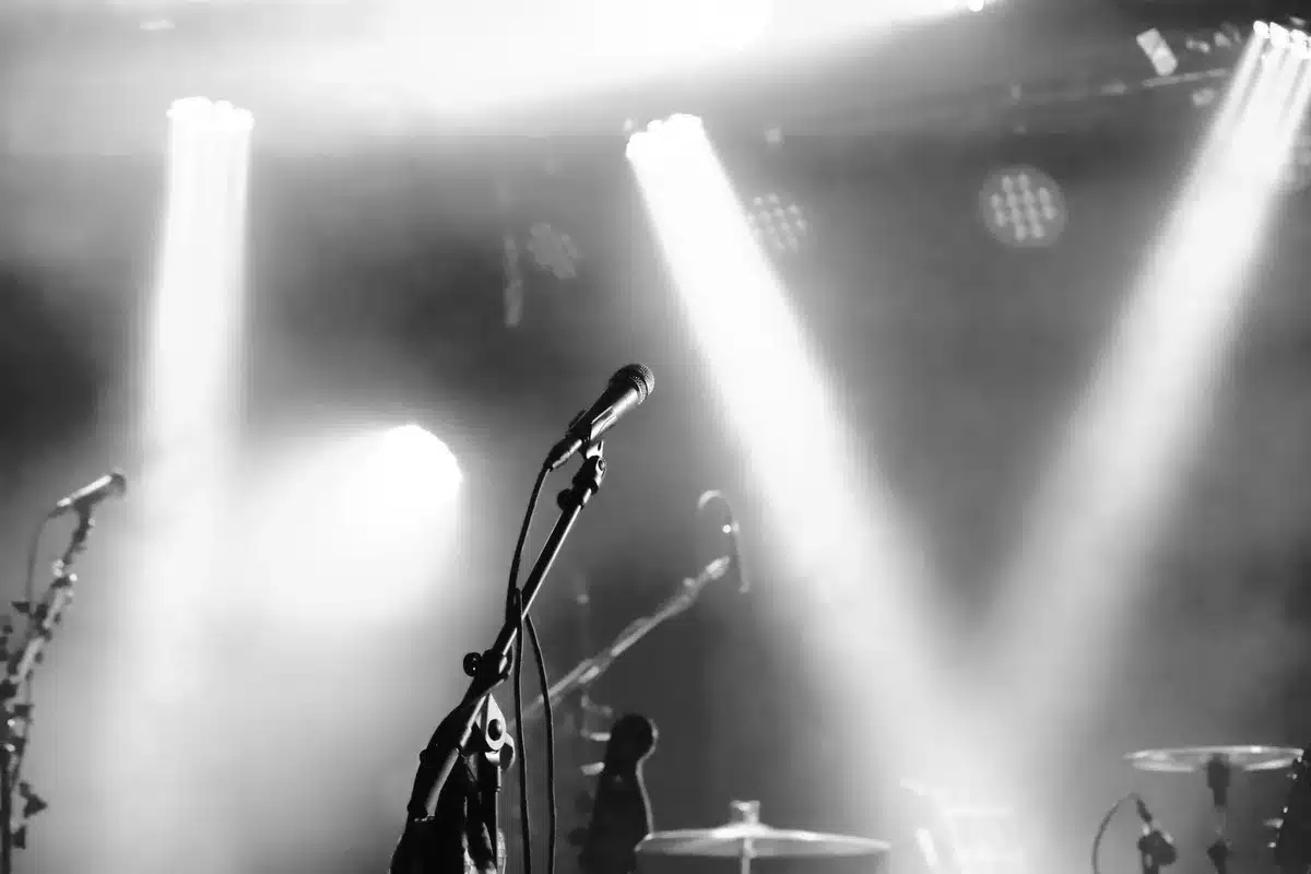 Palco da concerto vuoto con microfono e riflettori spenti, simbolo della sospensione del tour