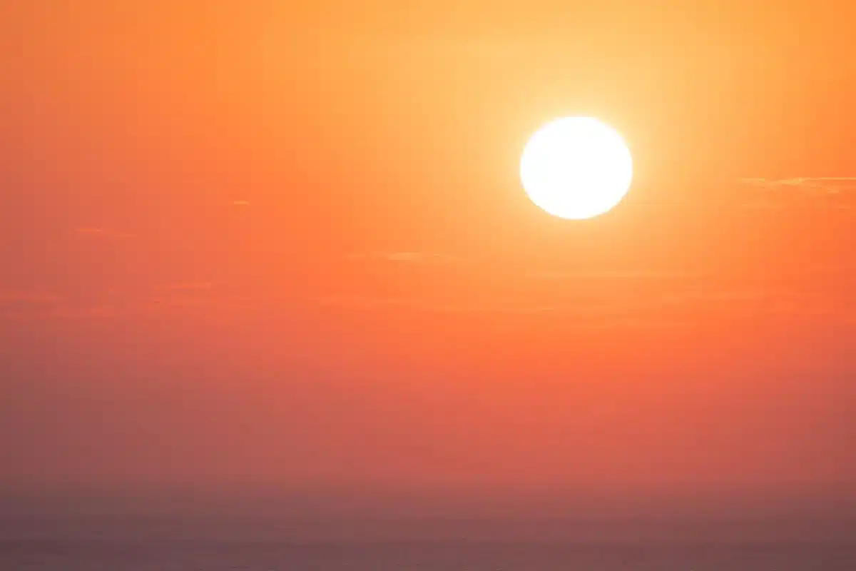 Tramonto dorato che illumina il mare calmo con una scia luminosa continua sull'orizzonte