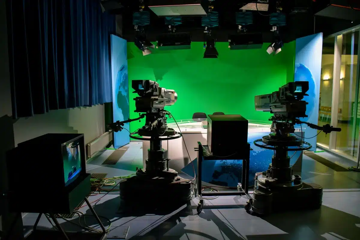 Studio televisivo con scrivania, microfono e monitor per trasmissione di attualità