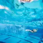 Subacqueo in immersione in una piscina termale profonda con acqua azzurra e strutture sommerse visibili