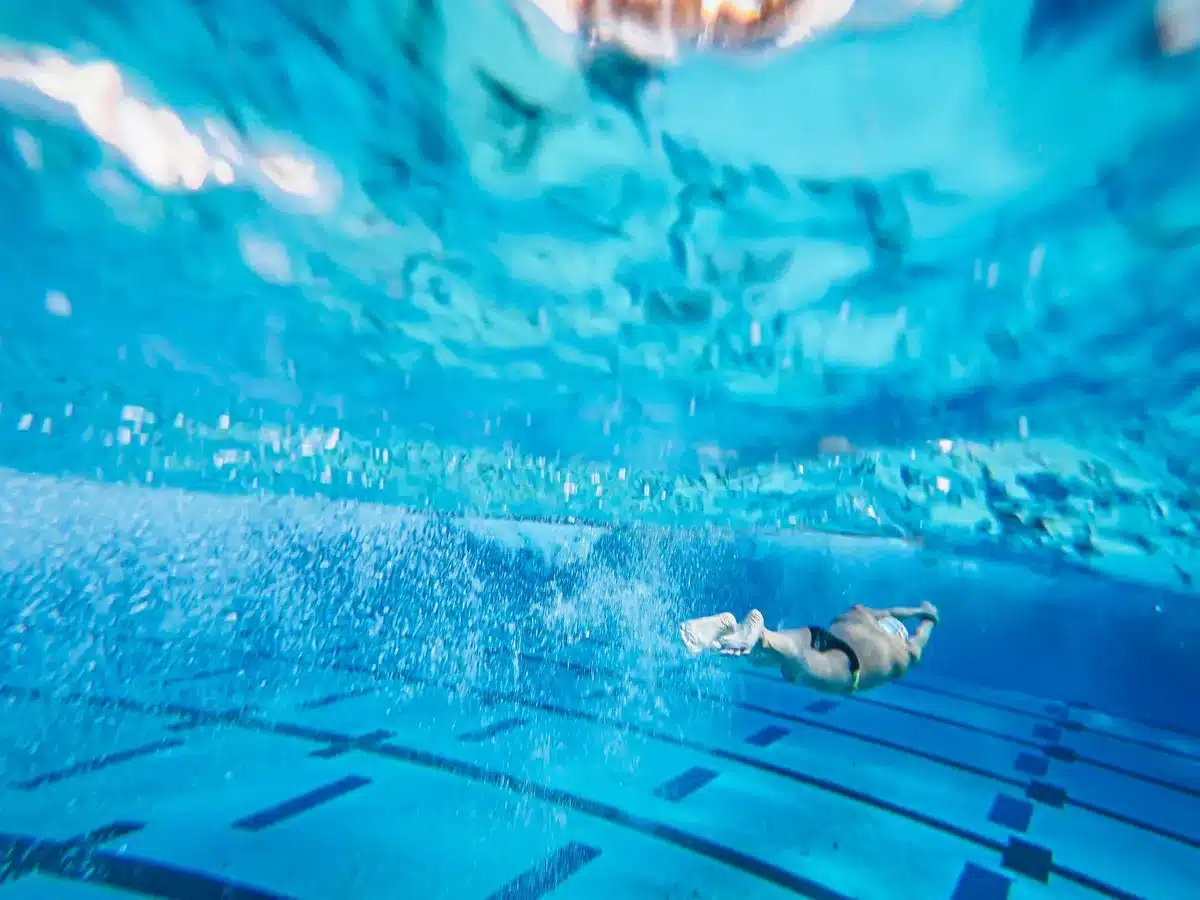 Subacqueo in immersione in una piscina termale profonda con acqua azzurra e strutture sommerse visibili