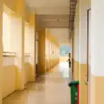 Corridoio di una residenza universitaria con stanze vuote e porte aperte