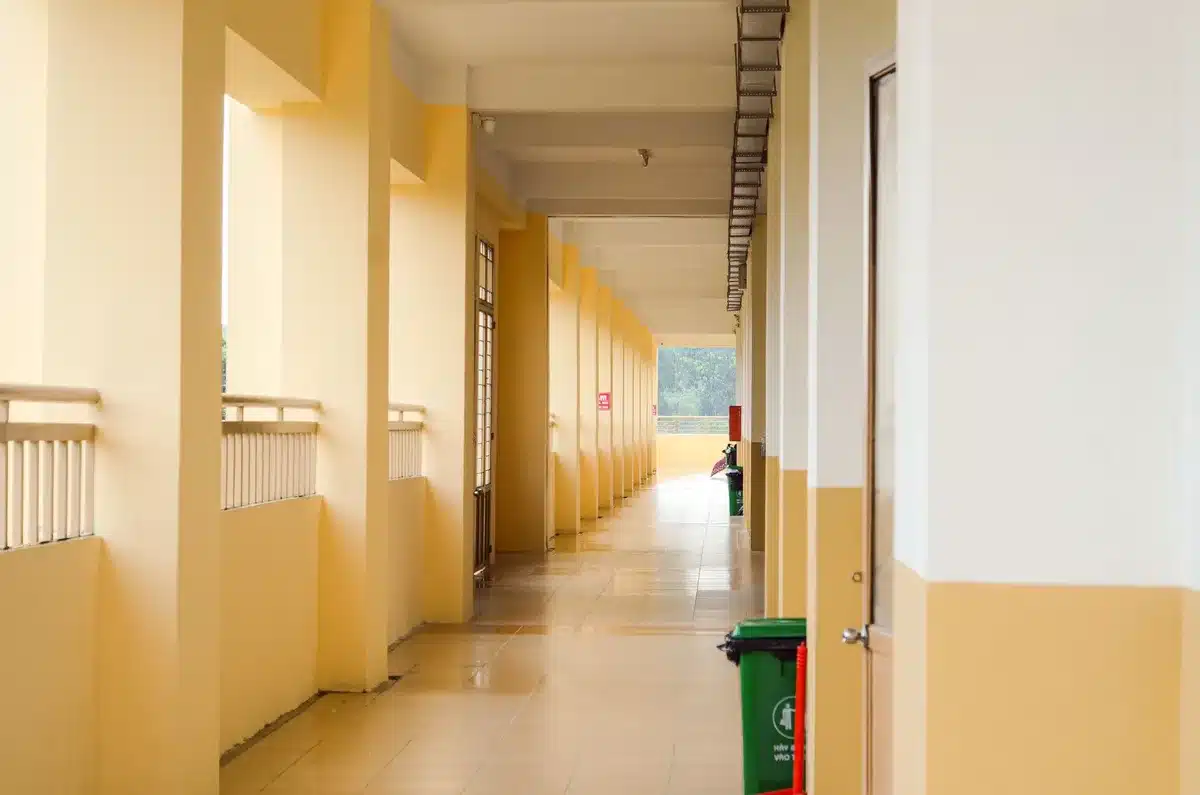 Corridoio di una residenza universitaria con stanze vuote e porte aperte