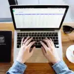 Scrivania di docente con laptop, libri e modulo voucher, scena anonima