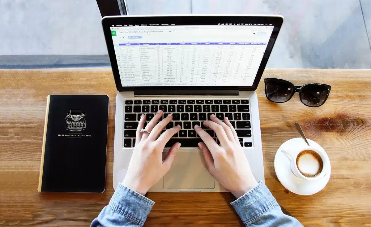 Scrivania di docente con laptop, libri e modulo voucher, scena anonima