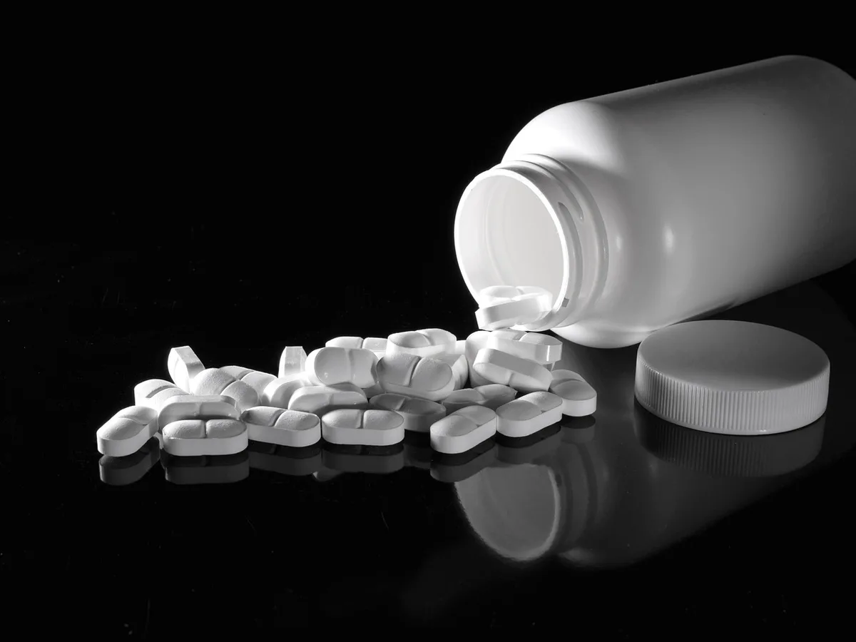 Busta di medicinali e pillole, con una borsa da viaggio sullo sfondo