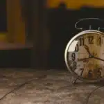 Mani anonime che sistemano capi vintage su un tavolo in legno, atmosfera anni '70