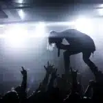 Palco vuoto con microfono e chitarra, pubblico sfocato sullo sfondo