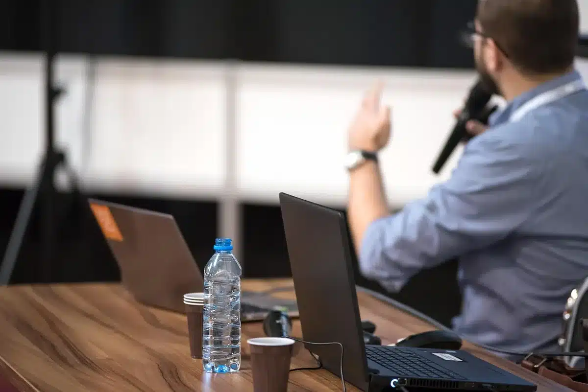 Tavolo di conferenza con sagome di delegati, microfoni e documenti, luce neutra