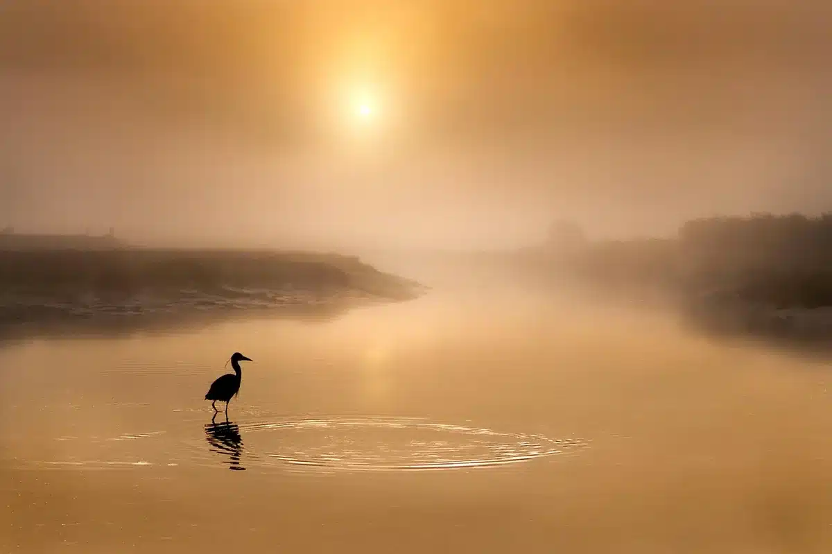 Pontile al tramonto con figure in silhouette, lanterna e maschera tradizionale in primo piano